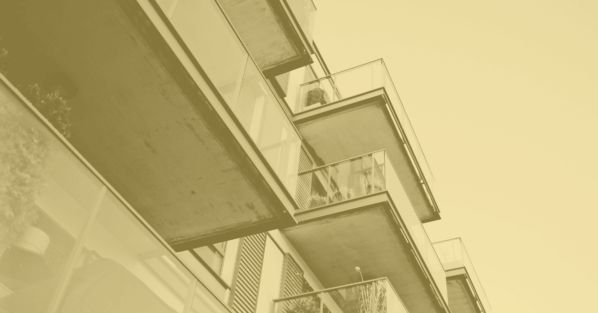 Vue en contre-plongée de balcons en saillie, avec garde-corps de verre et dalles de béton.